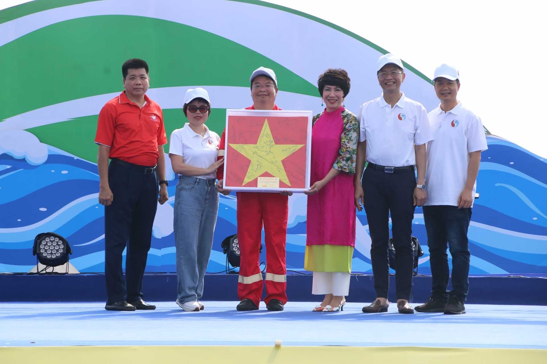 Ông Trần Quang Dũng, Trưởng ban Truyền thông và Văn hóa doanh nghiệp PetroVietnam cùng đại diện Ban công nghệ an toàn môi trường, BIENDONG POC trao tặng lá cờ cho của cán bộ nhân viên trên giàn Hải Thạch - Mộc Tinh cho đại diện Ban tổ chức Tuần lễ biển và hải đảo Việt Nam.